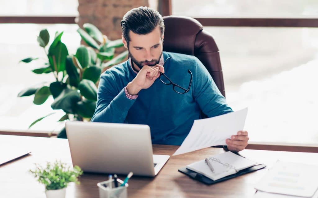 um homem sentado em uma mesa com um laptop e papéis