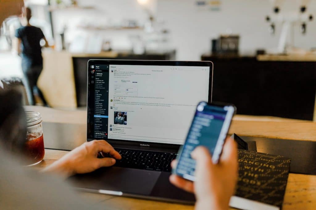 uma pessoa sentada à mesa com um laptop e um telefone celular