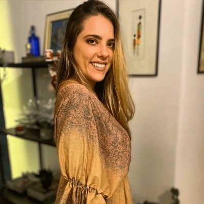 uma mulher parada em uma sala de estar sorrindo para a câmera