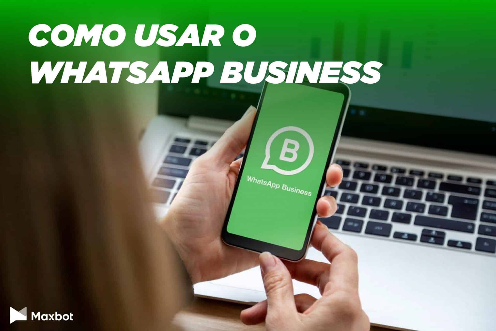 Mulher segurando celular com Whatsapp Business aberto em frente a um computador e legenda 